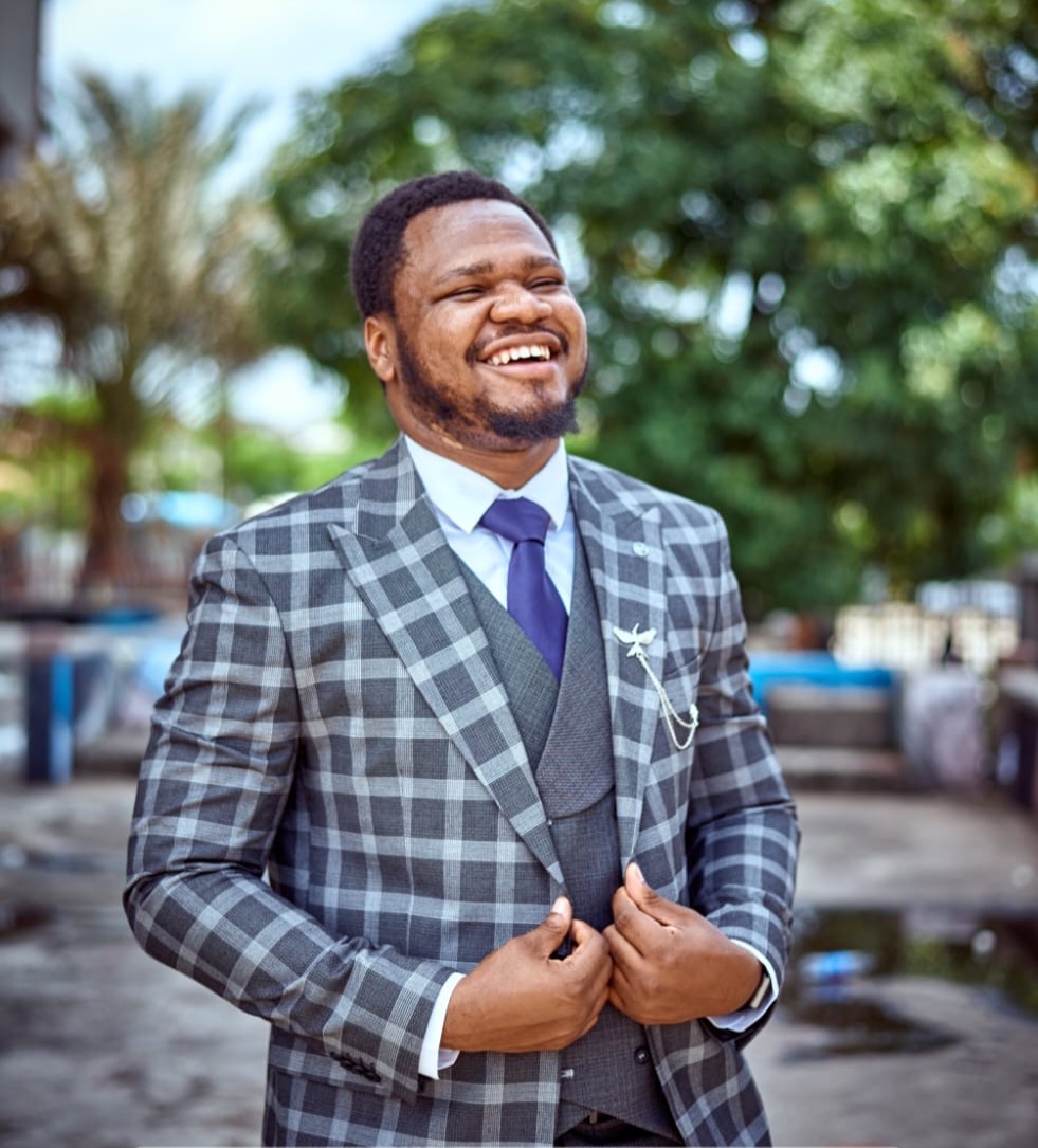 Victor Akan smiling, in a checked suit